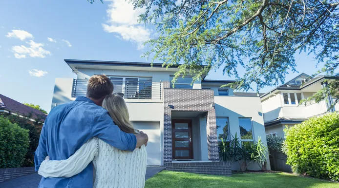 Paar steht umarmt vor seinem Einfamilienhaus